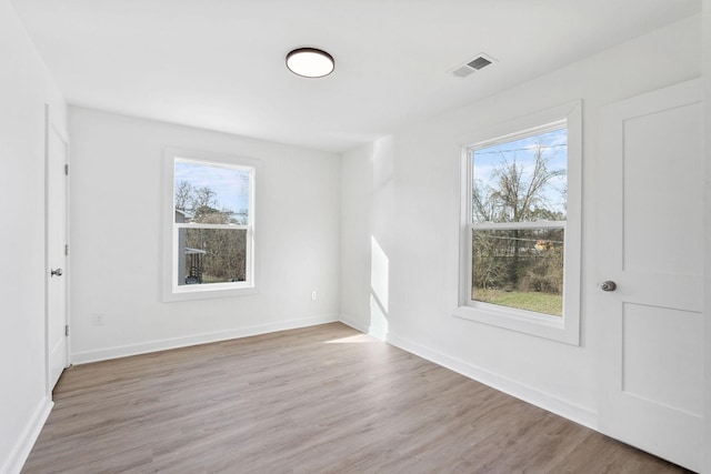 spare room with visible vents, baseboards, and wood finished floors