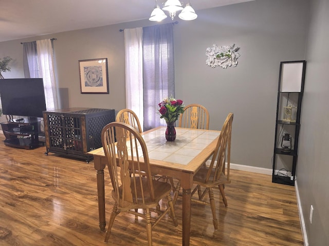 dining space featuring a notable chandelier, plenty of natural light, baseboards, and wood finished floors