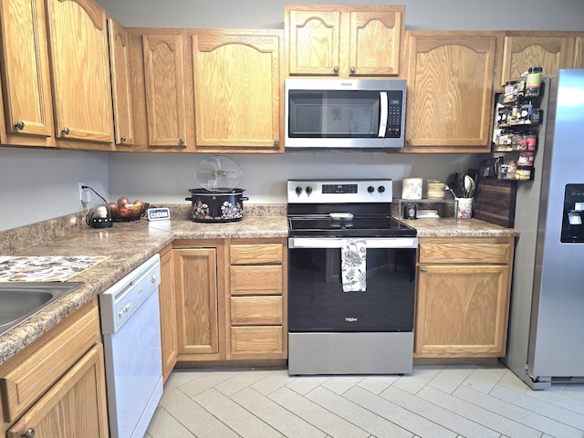 kitchen featuring light wood-style flooring, stainless steel appliances, and light countertops