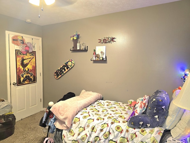 bedroom with carpet floors, ceiling fan, and a textured ceiling