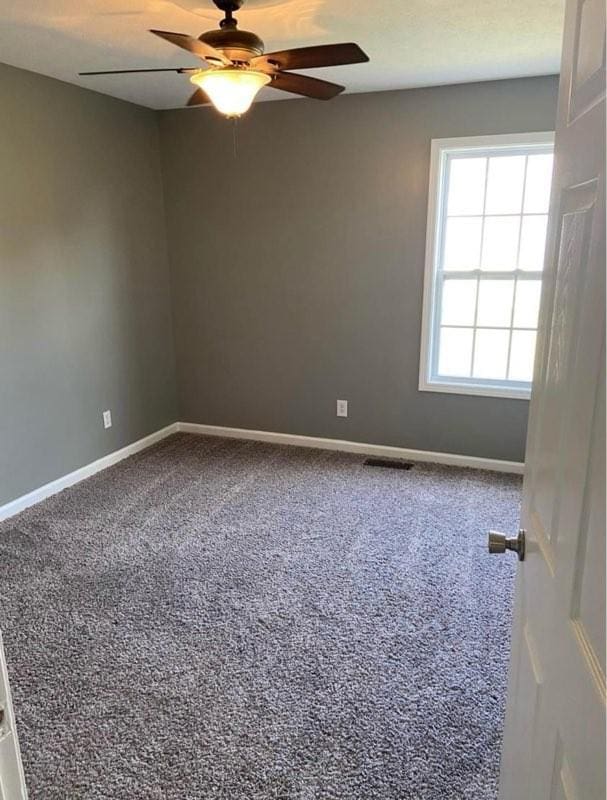 carpeted spare room with ceiling fan, visible vents, and baseboards