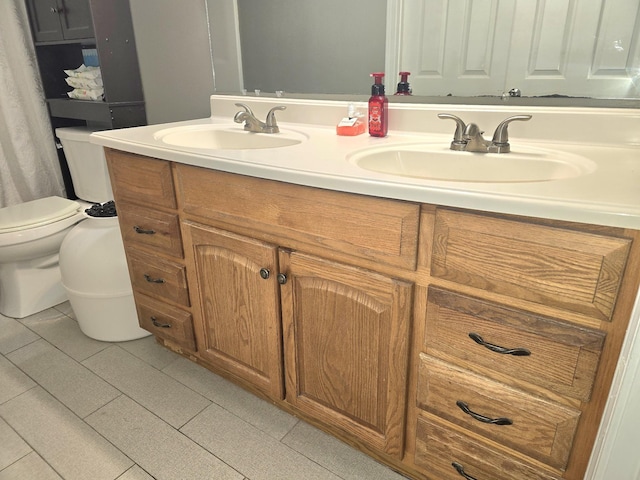 bathroom with toilet, double vanity, and a sink