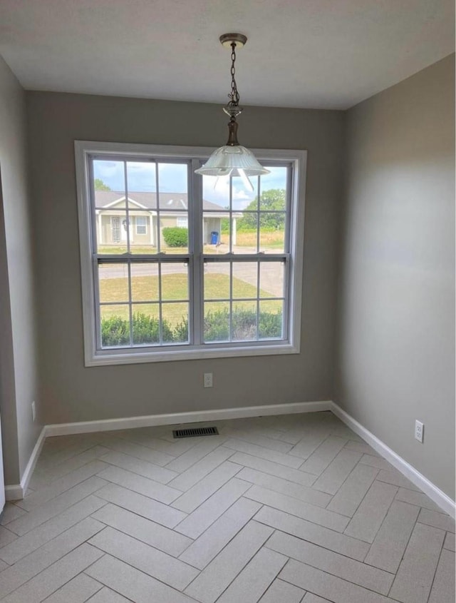 unfurnished dining area with baseboards and visible vents