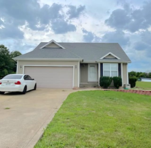 ranch-style home featuring an attached garage, concrete driveway, and a front yard