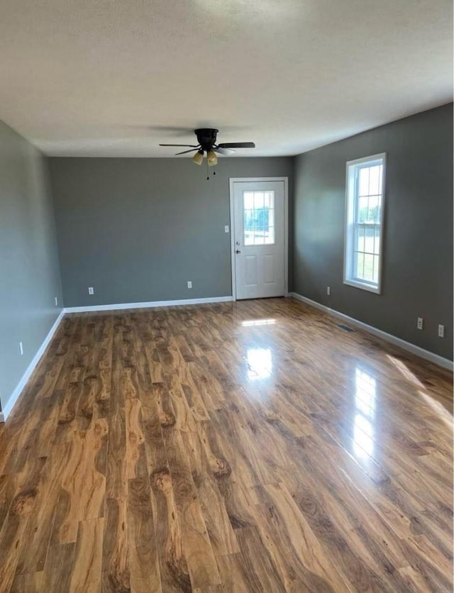 spare room with dark wood-style flooring, a wealth of natural light, and baseboards