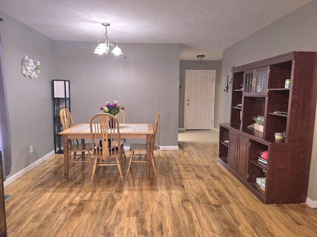 dining space featuring an inviting chandelier, wood finished floors, and baseboards