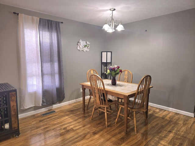 dining area featuring baseboards, wood finished floors, visible vents, and a notable chandelier