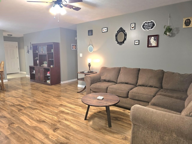 living room featuring ceiling fan, baseboards, and wood finished floors