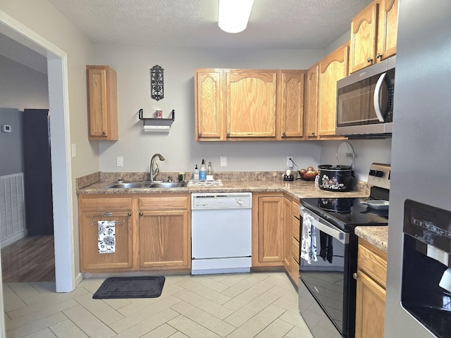 kitchen with a textured ceiling, appliances with stainless steel finishes, light countertops, and a sink