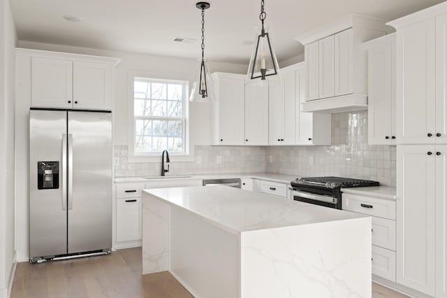 kitchen with tasteful backsplash, a kitchen island, appliances with stainless steel finishes, and a sink