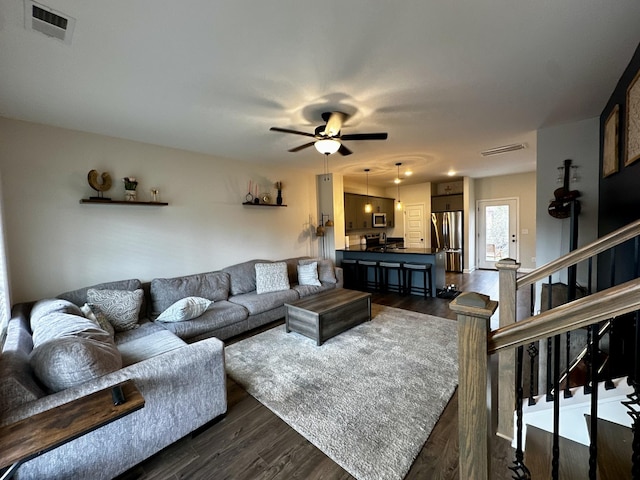 living room with visible vents, dark wood finished floors, stairway, and ceiling fan