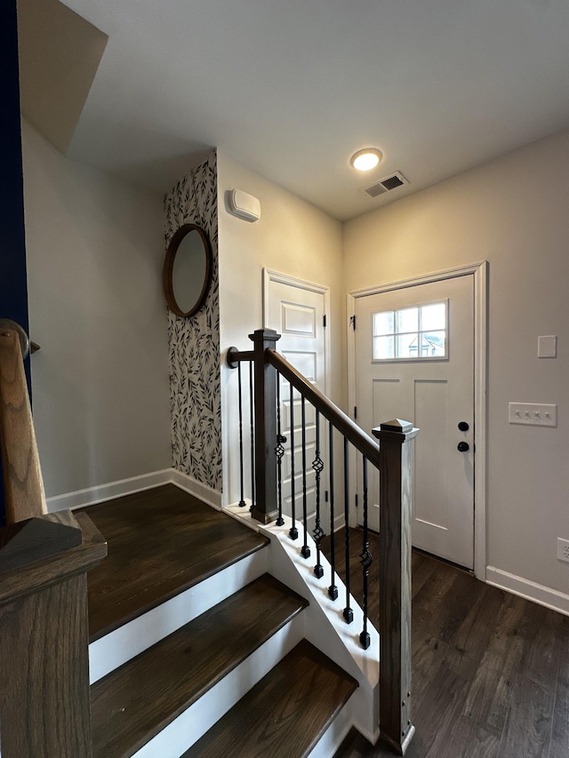 stairway featuring wood finished floors, visible vents, and baseboards