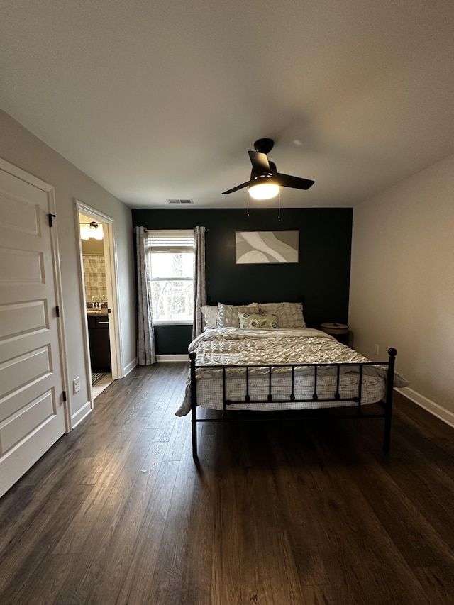 bedroom with dark wood-type flooring, visible vents, connected bathroom, and baseboards