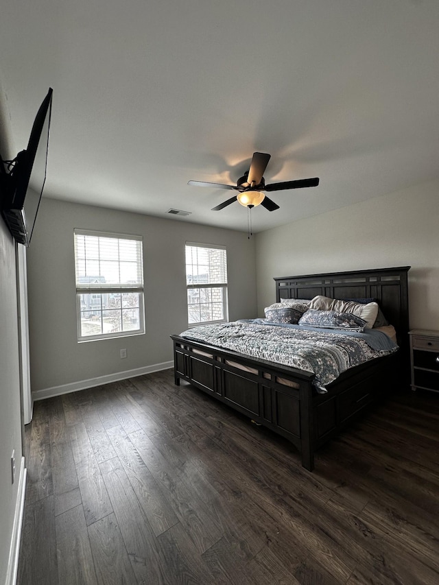 bedroom with baseboards, multiple windows, visible vents, and dark wood finished floors