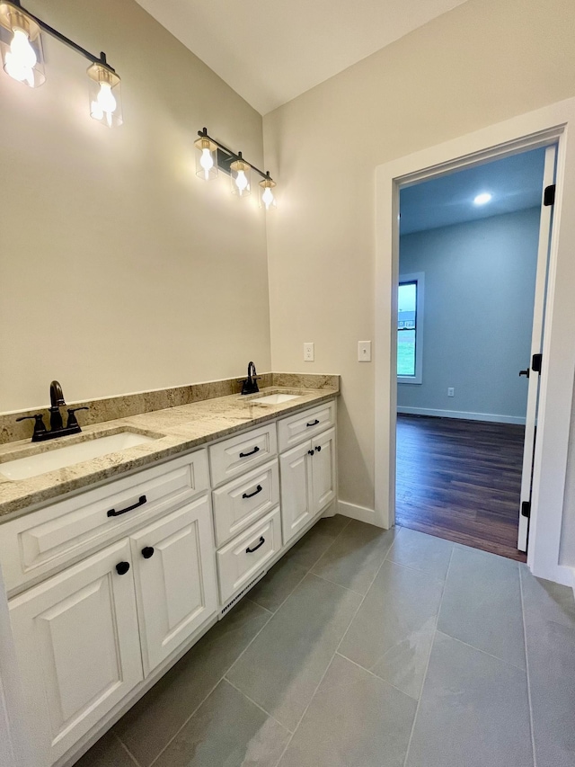 full bathroom featuring double vanity, tile patterned flooring, a sink, and baseboards