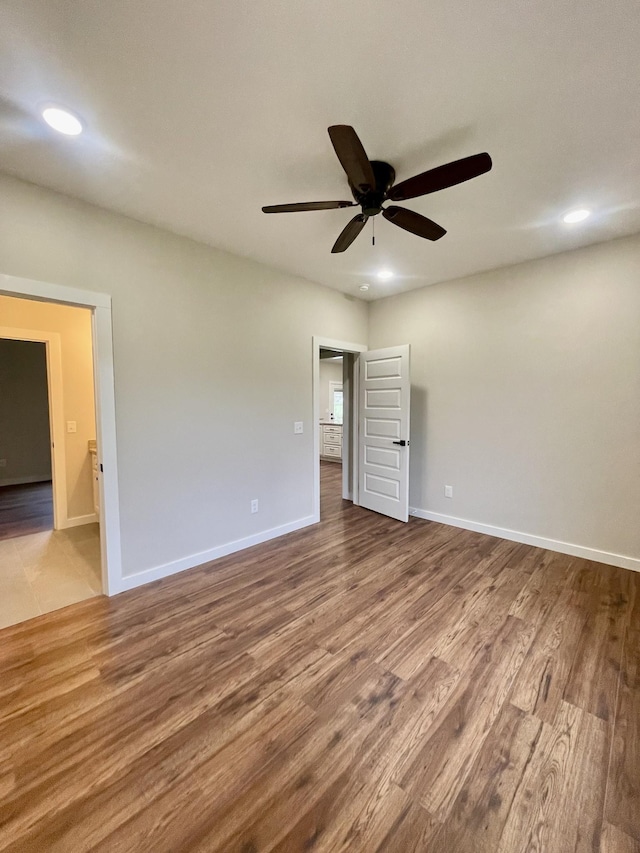 empty room with baseboards, wood finished floors, and recessed lighting