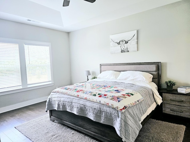 bedroom featuring a ceiling fan, baseboards, visible vents, and wood finished floors