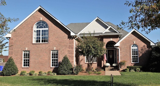 traditional-style home with brick siding and a front lawn