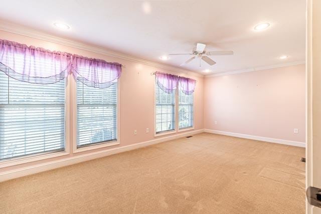 empty room with baseboards, light colored carpet, and crown molding