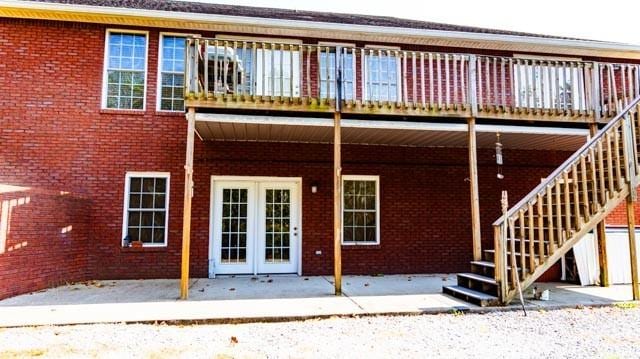 rear view of property with brick siding and stairs