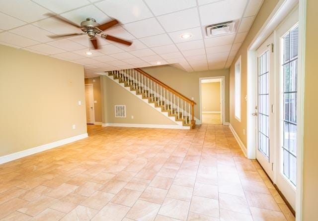 empty room with baseboards, stairs, visible vents, and a drop ceiling