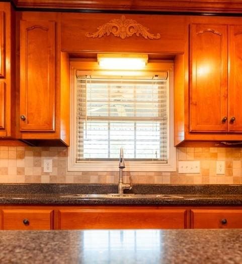 kitchen featuring dark stone counters, a sink, and decorative backsplash