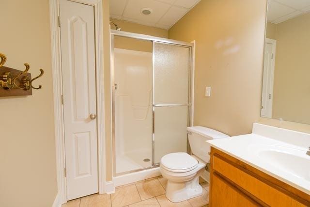 bathroom with toilet, a shower stall, vanity, and tile patterned floors