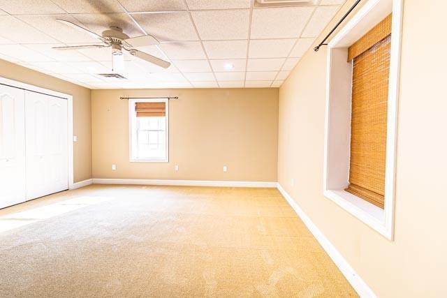 unfurnished bedroom featuring light colored carpet, visible vents, baseboards, and a drop ceiling