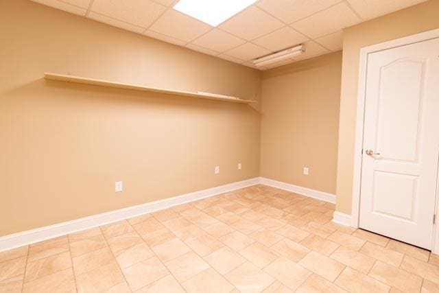 spare room with a paneled ceiling and baseboards