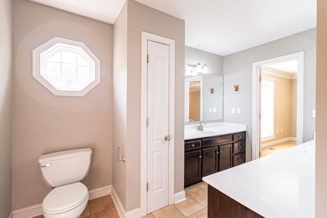 bathroom with toilet, baseboards, vanity, and tile patterned floors