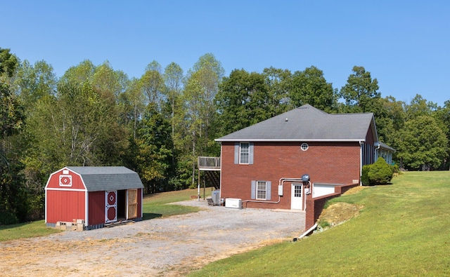 view of side of property featuring a storage shed, brick siding, an outdoor structure, a yard, and driveway