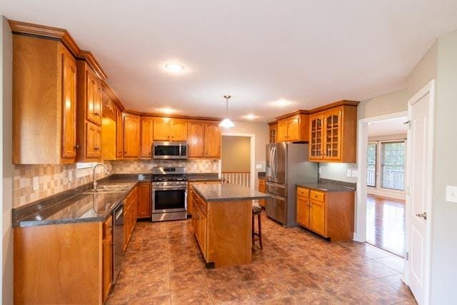 kitchen with brown cabinetry, glass insert cabinets, stainless steel appliances, and a sink