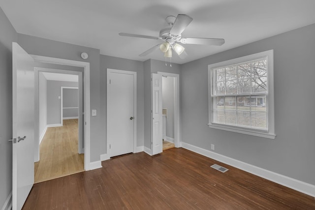 unfurnished bedroom featuring ceiling fan, wood finished floors, visible vents, baseboards, and a closet