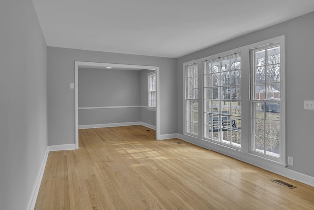 spare room with light wood-style flooring, visible vents, and baseboards