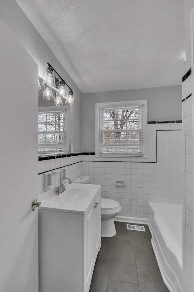 bathroom with a wealth of natural light, visible vents, vanity, and toilet