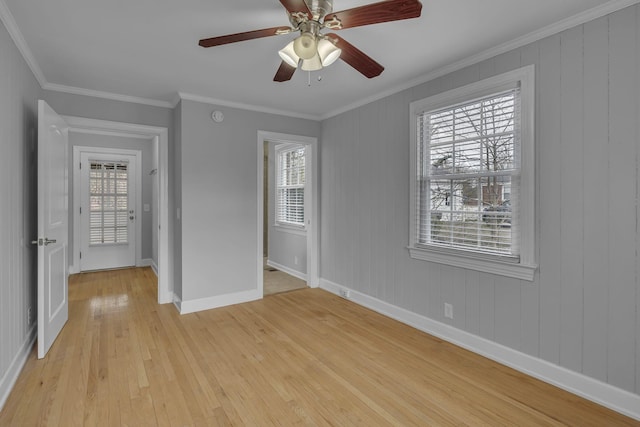 interior space with ornamental molding, multiple windows, light wood-style flooring, and baseboards