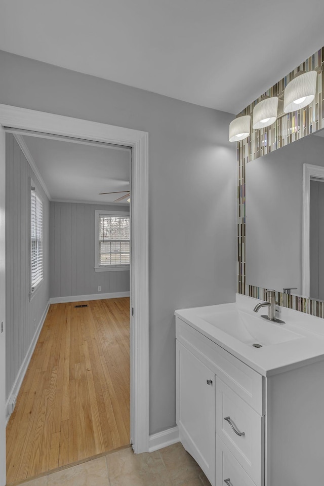 bathroom with ceiling fan, wood finished floors, visible vents, vanity, and baseboards