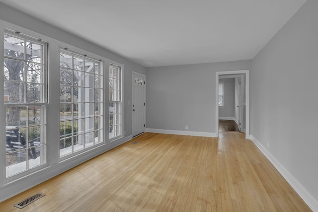 unfurnished room with light wood finished floors, baseboards, and visible vents