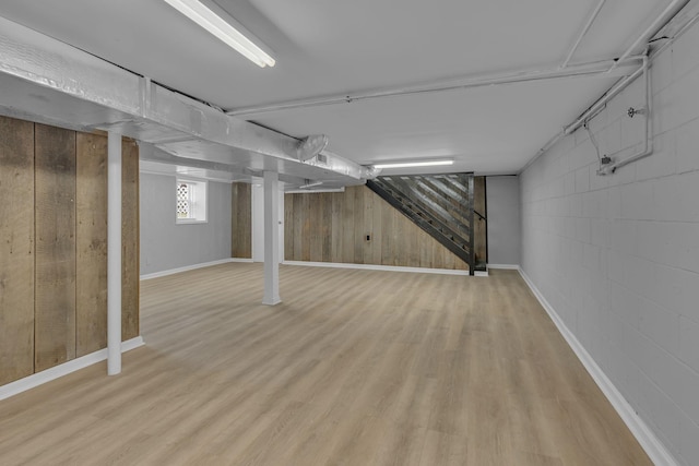 basement with wood finished floors, concrete block wall, and baseboards