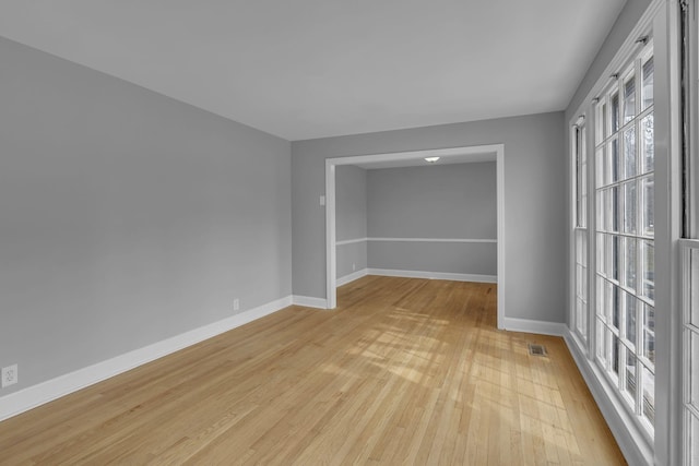 unfurnished room with light wood finished floors, visible vents, and baseboards