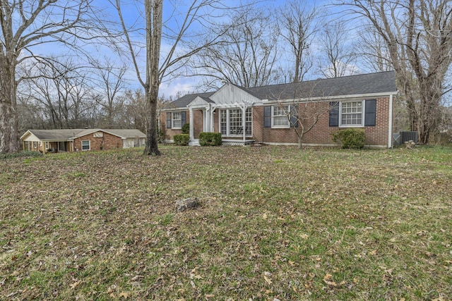 view of front facade featuring brick siding, a front lawn, and central AC unit