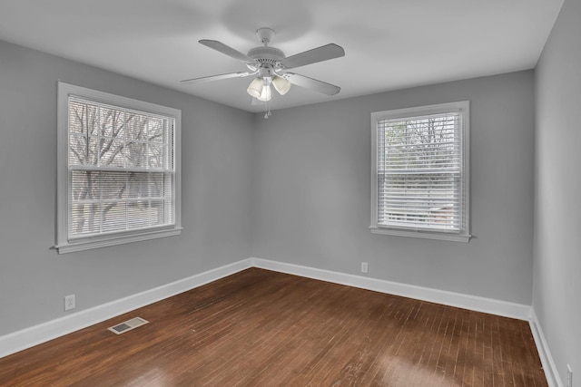 spare room featuring dark wood-type flooring, visible vents, baseboards, and a ceiling fan