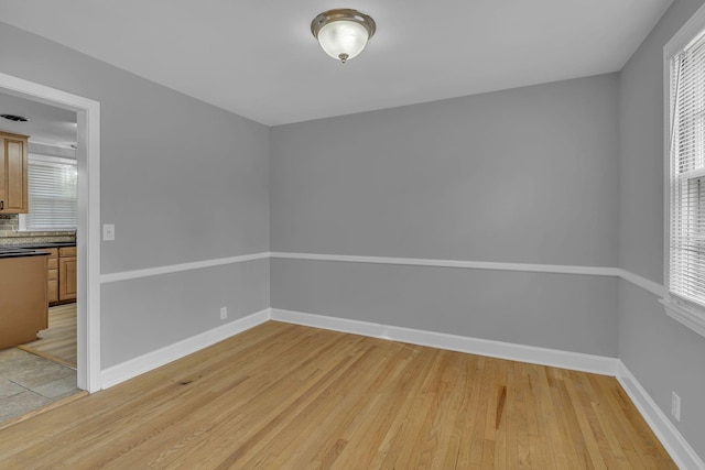 empty room featuring light wood-type flooring and baseboards