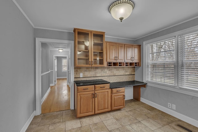 kitchen with dark countertops, visible vents, decorative backsplash, ornamental molding, and baseboards