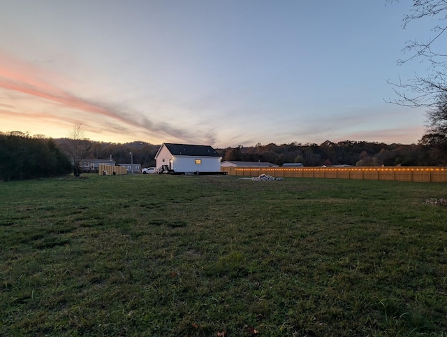 yard at dusk featuring a rural view and fence