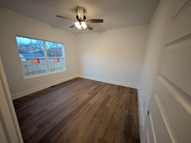 empty room with dark wood-style floors, ceiling fan, visible vents, and baseboards