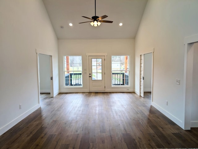 unfurnished living room with high vaulted ceiling, dark wood-type flooring, and baseboards