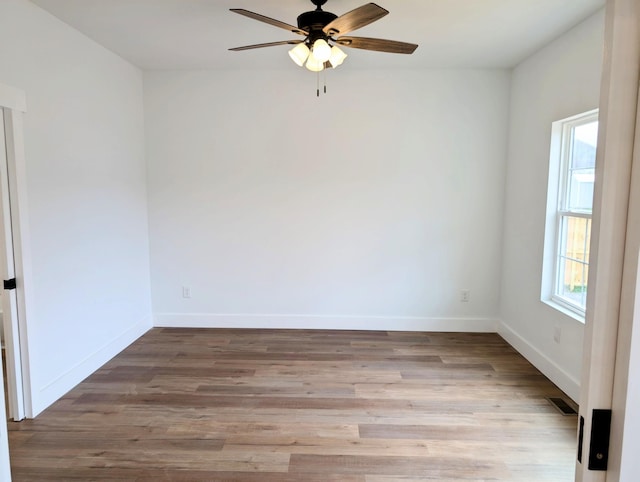 spare room featuring light wood-style floors, visible vents, baseboards, and a ceiling fan