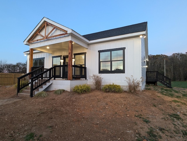 view of front of house with covered porch, board and batten siding, and roof with shingles