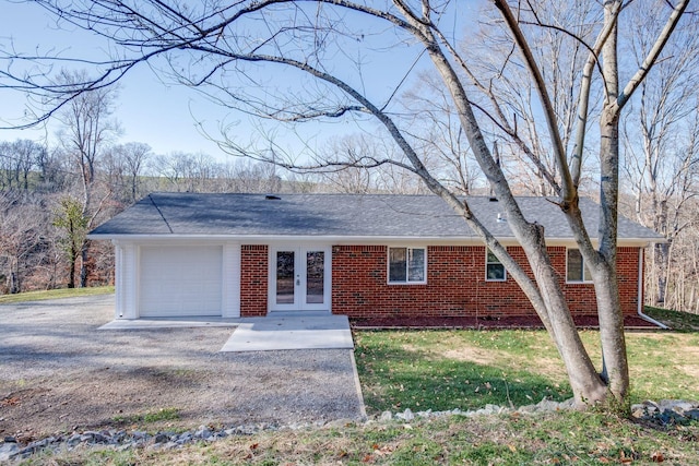 ranch-style house featuring a garage, gravel driveway, french doors, a front lawn, and brick siding